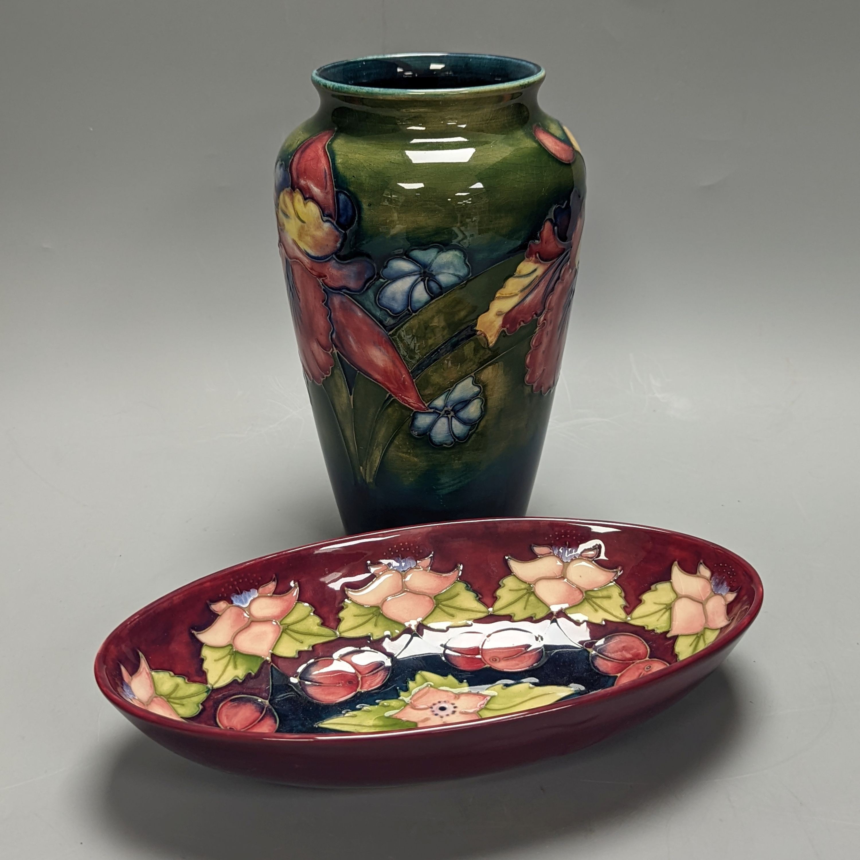 A Moorcroft orchid pattern green glazed vase, signed William Moorcroft to underside and a similar maroon dish, initialled ‘BM’ and M.C.C 286 to underside, 21cm